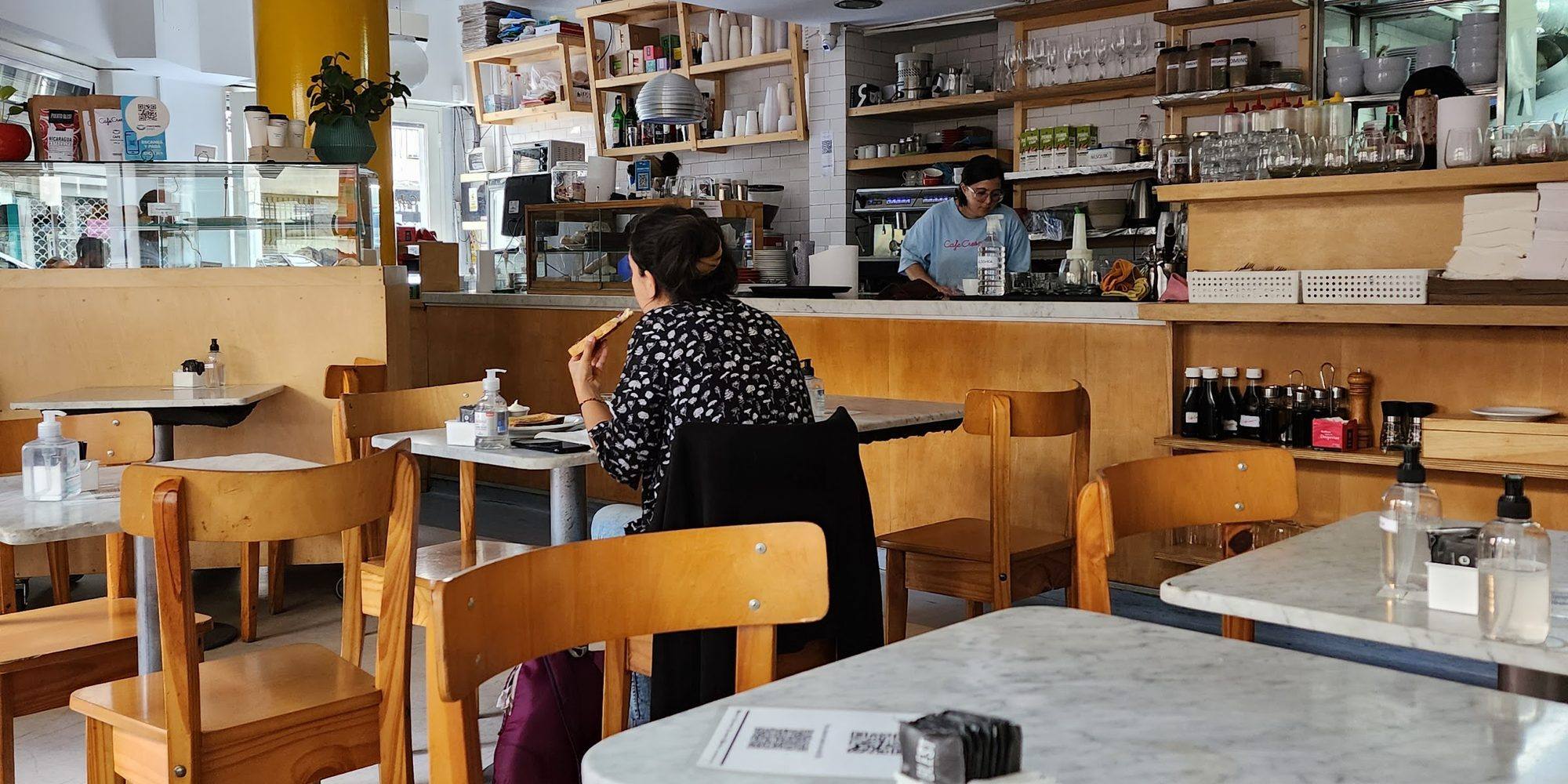 Salón de Café Crespín con mesas de mármol y estanterías